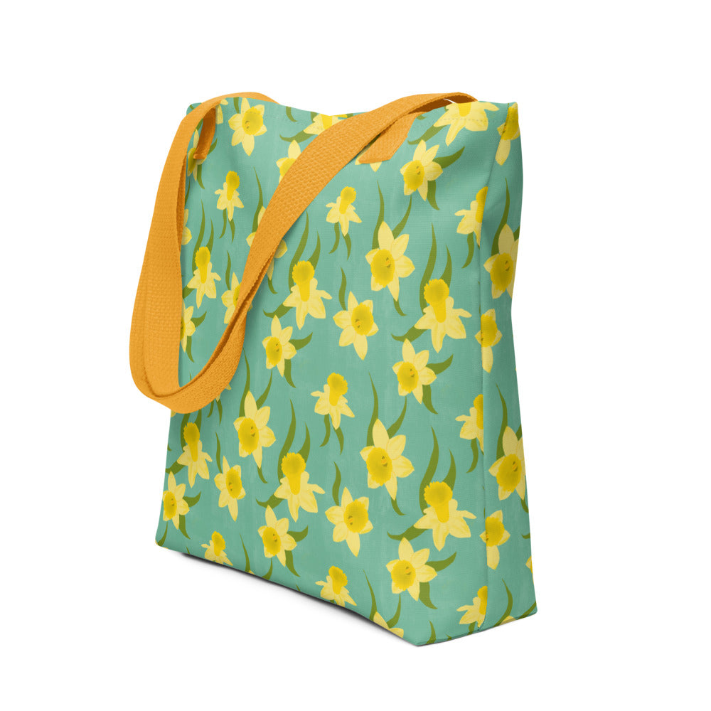 Tote bag with yellow Daffodil floral pattern on a teal background by Carmel Rimmer. Item is photographed on a white background.