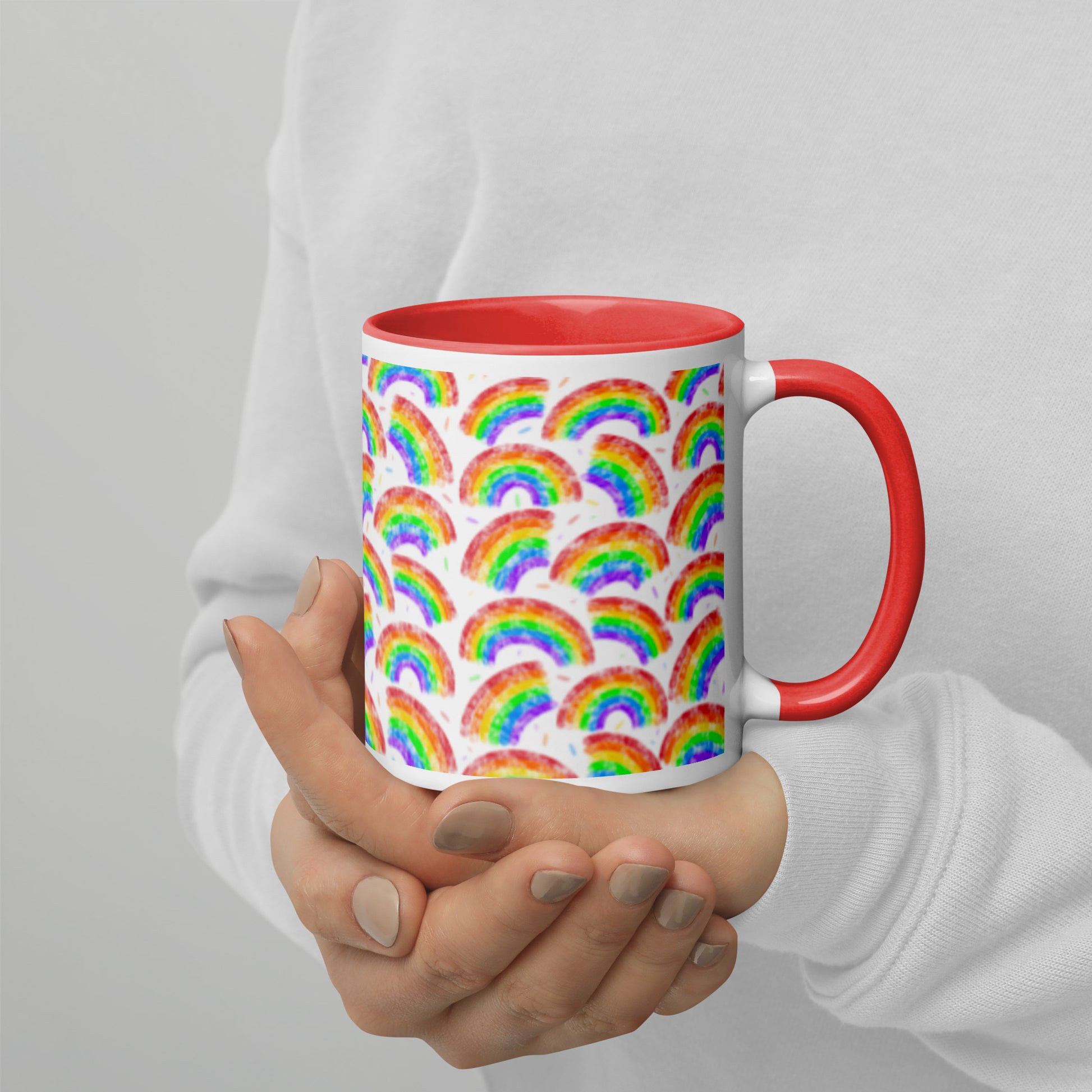 Mug with rainbow pattern by Carmel Rimmer and a red interior held by a person against a plain background