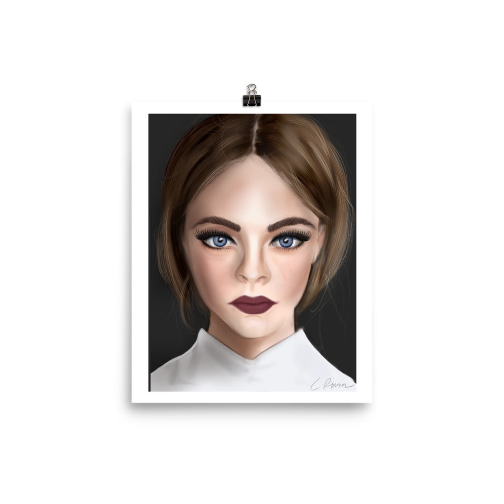 A framed poster print by Carmel Rimmer featuring a portrait of a woman with blue eyes and short brown hair, wearing a white top, against a black background.